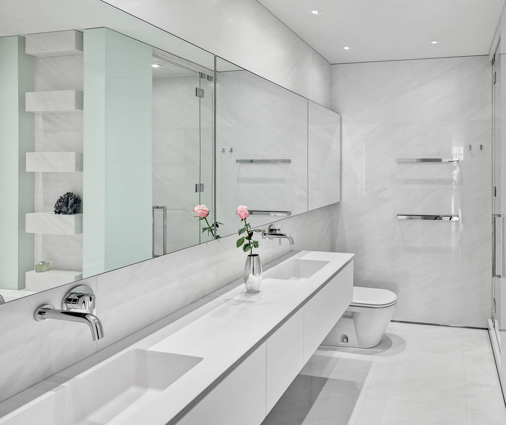 Modernes Badezimmer mit flächenbündigen Schrankfronten, weißen Schränken, weißen Fliesen, integriertem Waschbecken, weißem Boden und weißer Waschtischplatte in New York