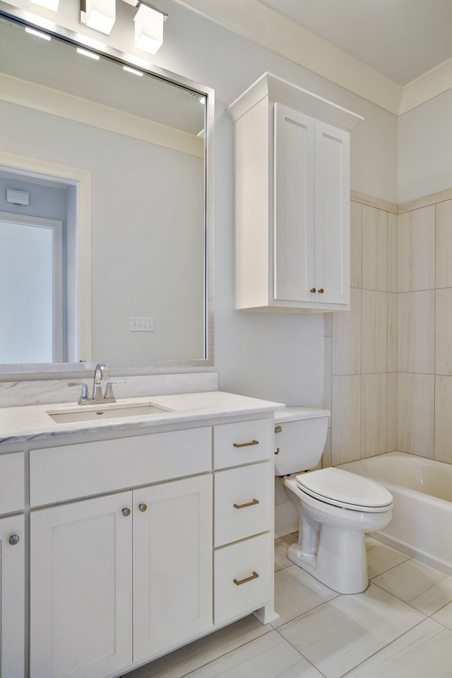 Cette photo montre une salle d'eau chic de taille moyenne avec un placard à porte shaker, des portes de placard blanches, un combiné douche/baignoire, WC séparés, un carrelage beige, des carreaux de porcelaine, un mur gris, un sol en carrelage de porcelaine, un lavabo encastré, un plan de toilette en marbre, un sol beige et une cabine de douche avec un rideau.