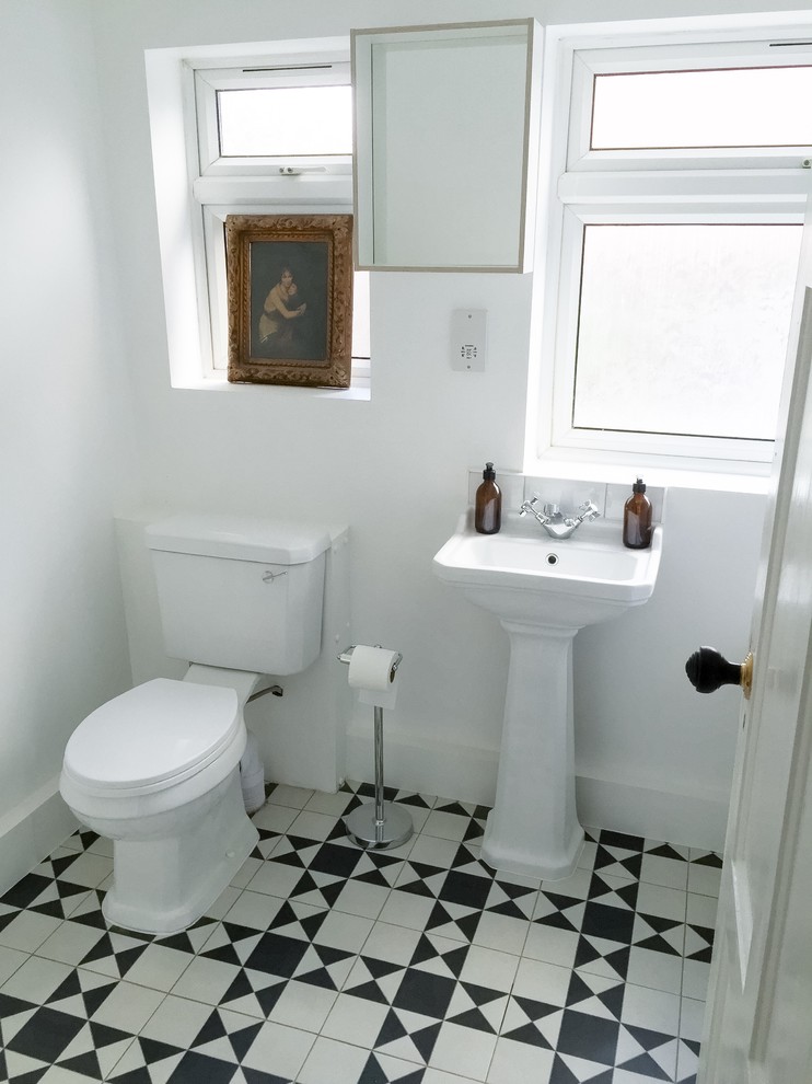 Inspiration for a small contemporary family bathroom in London with open cabinets, white cabinets, a built-in bath, a built-in shower, a two-piece toilet, black and white tiles, metro tiles, white walls, ceramic flooring and a pedestal sink.