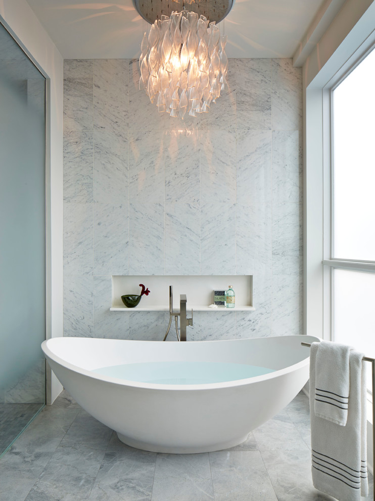 Modern inredning av ett badrum, med ett fristående badkar och vit kakel