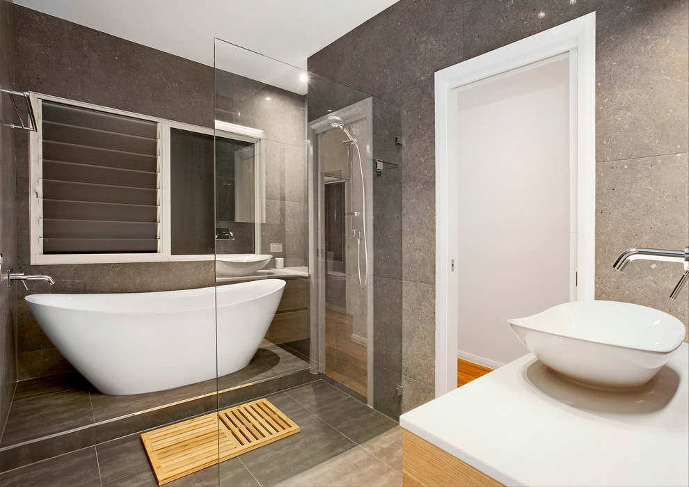 Exempel på ett mellanstort modernt en-suite badrum, med släta luckor, skåp i ljust trä, ett fristående badkar, en öppen dusch, en toalettstol med hel cisternkåpa, grå kakel, keramikplattor, grå väggar, klinkergolv i keramik, ett fristående handfat, grått golv och med dusch som är öppen