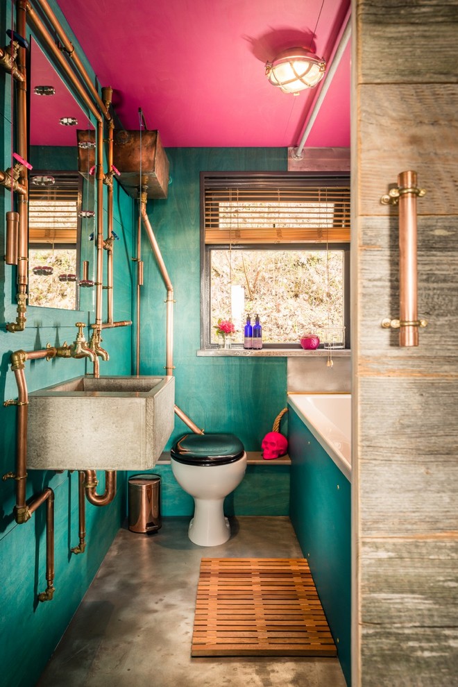 Foto på ett litet eklektiskt badrum för barn, med ett platsbyggt badkar, en dusch/badkar-kombination, en toalettstol med hel cisternkåpa, gröna väggar, betonggolv, ett avlångt handfat och grått golv