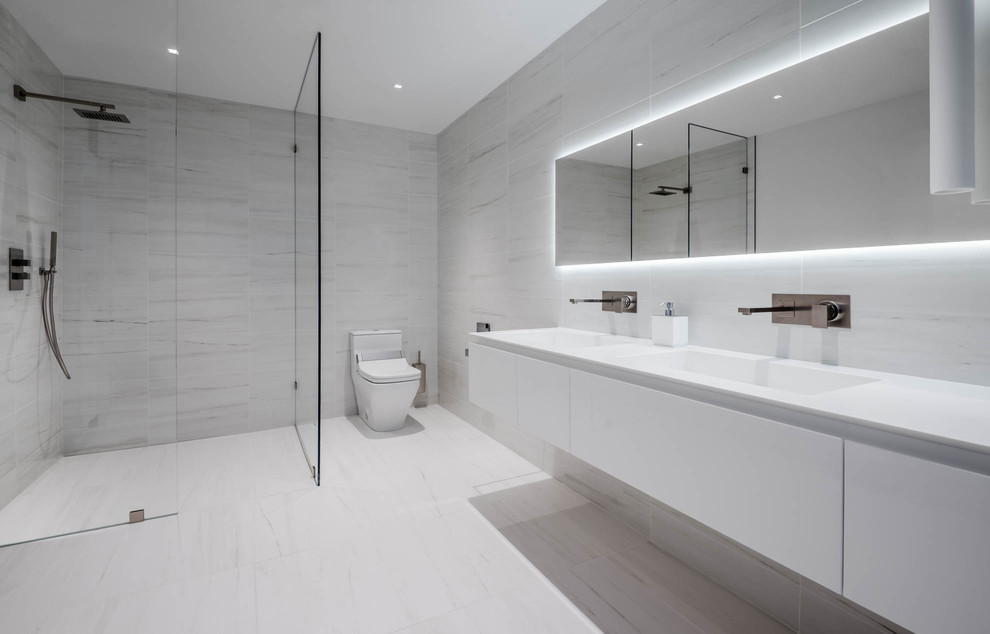 Design ideas for a large modern ensuite bathroom in Other with flat-panel cabinets, white cabinets, a freestanding bath, a walk-in shower, a one-piece toilet, white tiles, white walls, ceramic flooring, an integrated sink, solid surface worktops, white floors and an open shower.