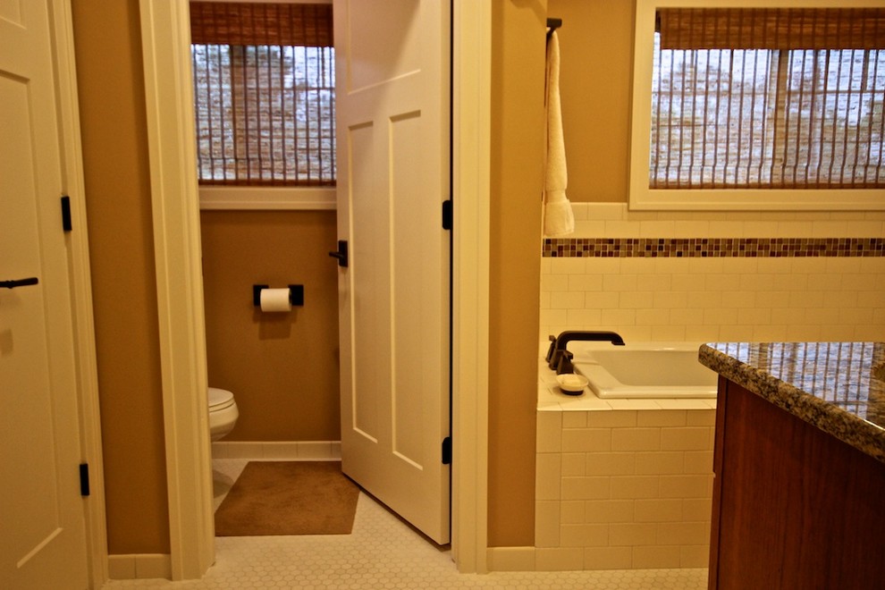 Cette photo montre une salle de bain principale craftsman en bois brun de taille moyenne avec un placard à porte shaker, une baignoire en alcôve, une douche d'angle, WC à poser, un carrelage blanc, un carrelage métro, un mur beige, un sol en carrelage de terre cuite, un lavabo encastré et un plan de toilette en granite.