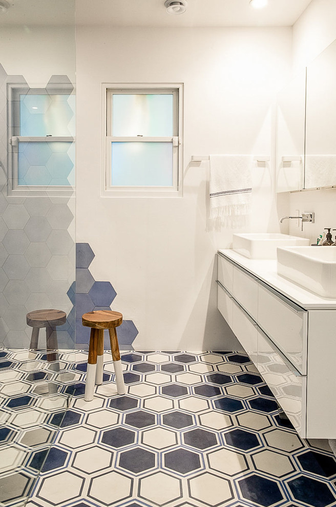 Imagen de cuarto de baño azulejo de dos tonos actual con lavabo sobreencimera, armarios con paneles lisos, puertas de armario blancas, ducha a ras de suelo, baldosas y/o azulejos multicolor y paredes blancas