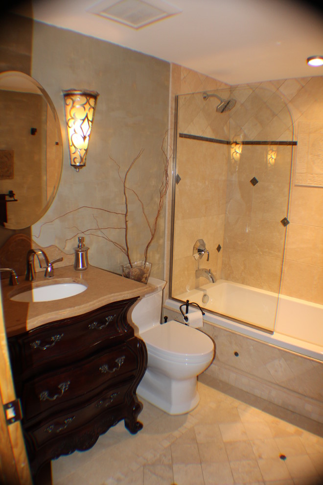 This is an example of a small traditional bathroom in Seattle with a submerged sink, freestanding cabinets, dark wood cabinets, limestone worktops, a built-in bath, a shower/bath combination, a one-piece toilet, beige tiles, stone tiles, green walls and travertine flooring.