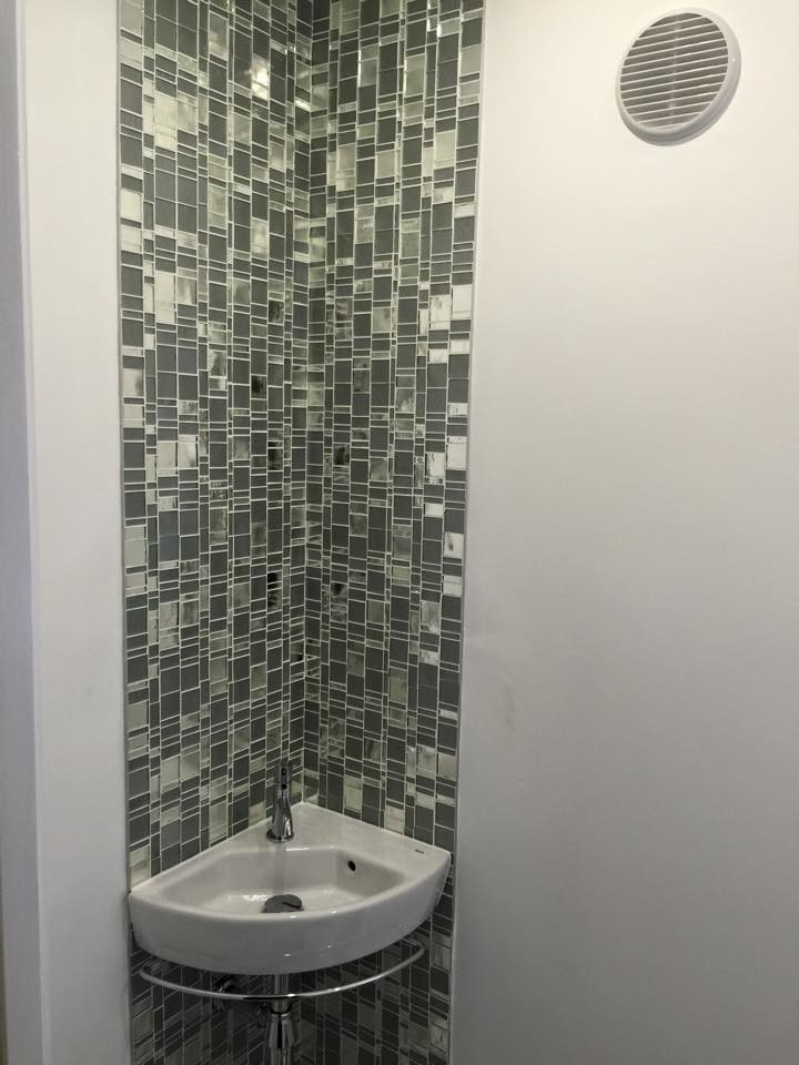 Foto de cuarto de baño actual con lavabo suspendido, baldosas y/o azulejos en mosaico y paredes blancas