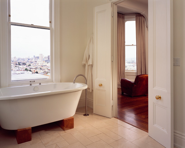 Foto på ett funkis badrum, med luckor med infälld panel, vita skåp och ett fristående badkar