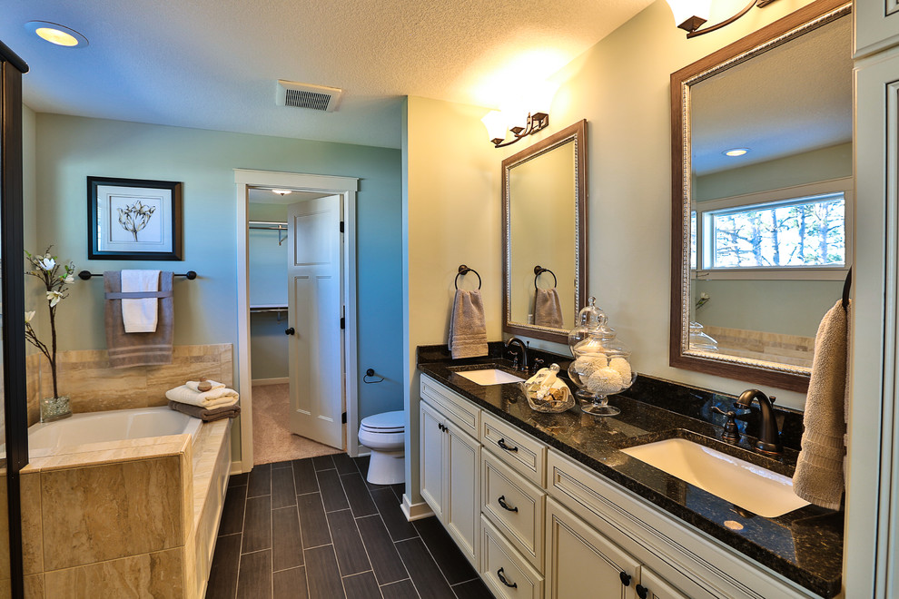 Example of a mid-sized classic master beige tile and ceramic tile ceramic tile corner shower design in Minneapolis with an undermount sink, beaded inset cabinets, white cabinets, granite countertops, an undermount tub, a one-piece toilet and green walls