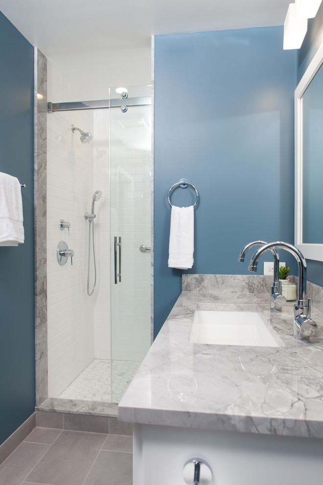 Klassisk inredning av ett litet grå grått en-suite badrum, med skåp i shakerstil, vita skåp, en dusch i en alkov, en toalettstol med hel cisternkåpa, vit kakel, tunnelbanekakel, blå väggar, klinkergolv i porslin, ett nedsänkt handfat, bänkskiva i kvarts, grått golv och dusch med skjutdörr