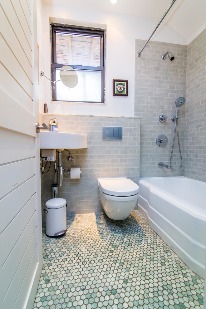 Exempel på ett litet maritimt badrum, med ett väggmonterat handfat, ett badkar i en alkov, en dusch/badkar-kombination, en vägghängd toalettstol, grön kakel, porslinskakel, vita väggar och klinkergolv i porslin