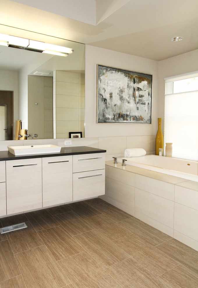 Example of a trendy beige tile drop-in bathtub design in Boise with a vessel sink, flat-panel cabinets, beige cabinets and beige walls