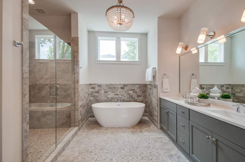 Inspiration for a large classic ensuite bathroom in Nashville with recessed-panel cabinets, grey cabinets, white tiles, engineered stone worktops, white worktops, a freestanding bath, an alcove shower, a two-piece toilet, marble tiles, white walls, marble flooring, a submerged sink, beige floors and a hinged door.
