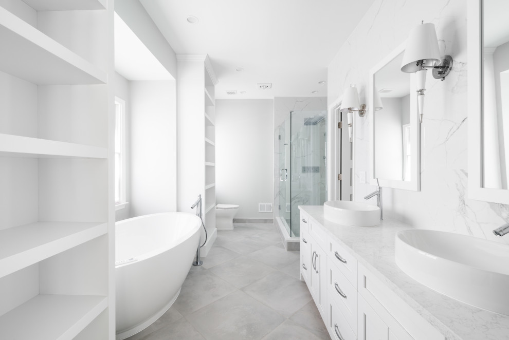 This is an example of a medium sized classic ensuite bathroom in Detroit with shaker cabinets, white cabinets, a freestanding bath, a corner shower, a one-piece toilet, white tiles, porcelain tiles, grey walls, porcelain flooring, a vessel sink, engineered stone worktops, grey floors, a hinged door, white worktops, a shower bench, double sinks and a built in vanity unit.