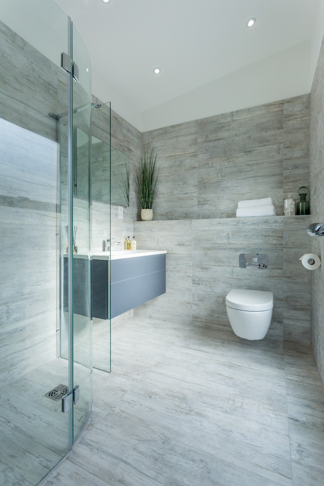 Design ideas for a large modern ensuite bathroom in Dorset with flat-panel cabinets, grey cabinets, a walk-in shower, a wall mounted toilet, beige tiles, ceramic tiles, ceramic flooring and a wall-mounted sink.