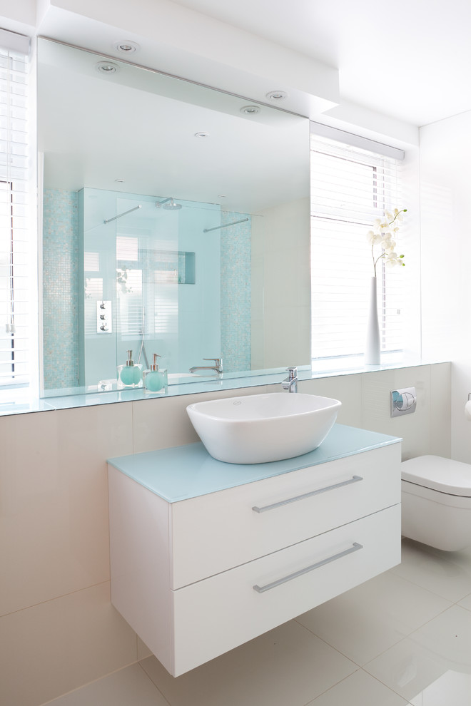 Inredning av ett modernt mellanstort badrum, med ett konsol handfat, bänkskiva i glas, en vägghängd toalettstol, vit kakel, porslinskakel och klinkergolv i porslin