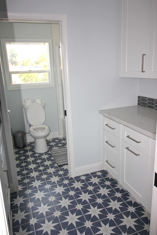 Inspiration pour une salle d'eau minimaliste de taille moyenne avec un placard à porte shaker, des portes de placard bleues, une baignoire encastrée, une douche d'angle, WC séparés, un carrelage blanc, des carreaux de porcelaine, un mur blanc, parquet foncé, un lavabo encastré, un plan de toilette en quartz, un sol marron, une cabine de douche à porte battante et un plan de toilette blanc.