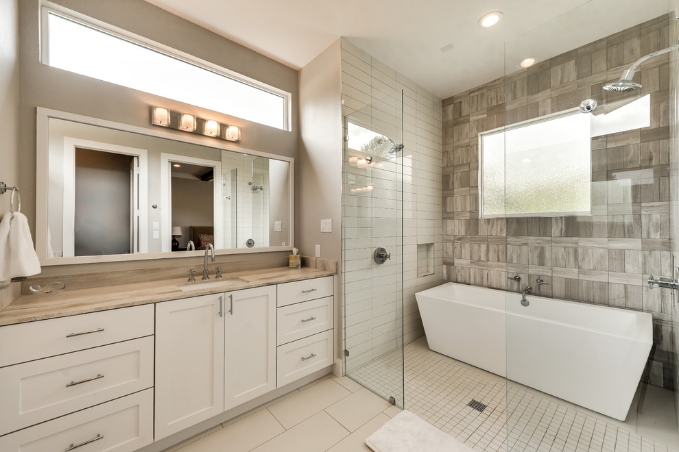 Свежая идея для дизайна: главная ванная комната в стиле кантри с фасадами в стиле шейкер, серыми фасадами, отдельно стоящей ванной, двойным душем, бежевой плиткой, плиткой из известняка, бежевыми стенами, полом из керамогранита, врезной раковиной, столешницей из известняка, бежевым полом и открытым душем - отличное фото интерьера