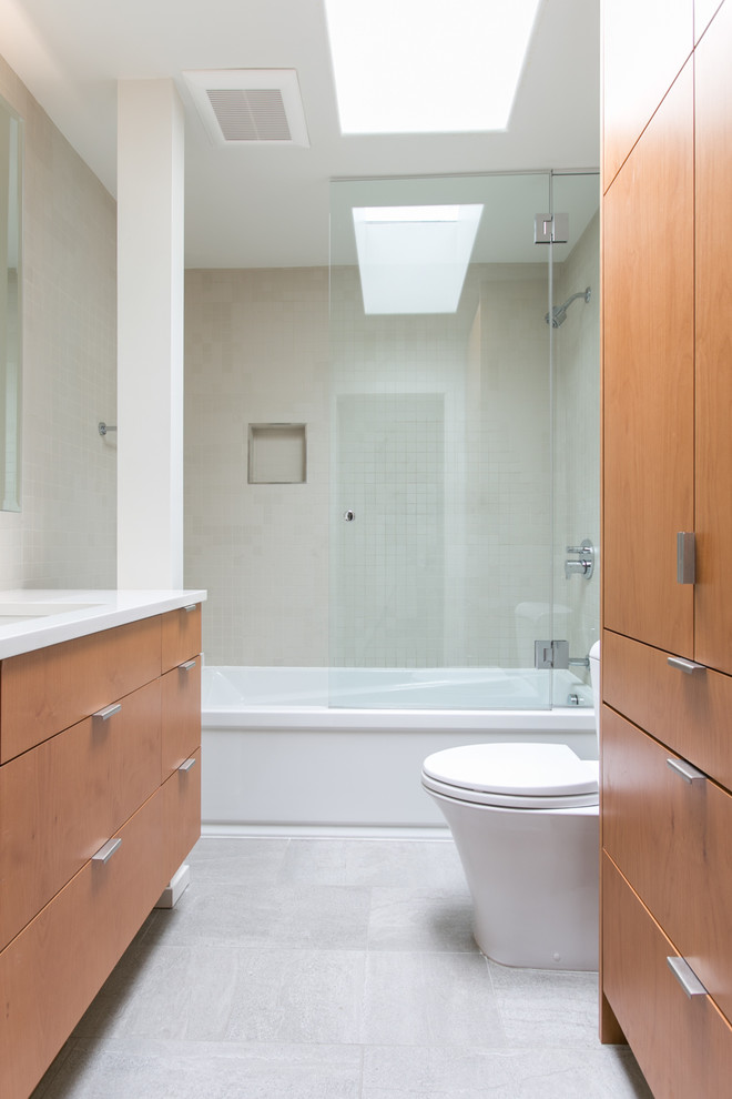 Bathroom - mid-sized contemporary kids' beige tile gray floor bathroom idea in Seattle with light wood cabinets, a one-piece toilet, a hinged shower door and white countertops