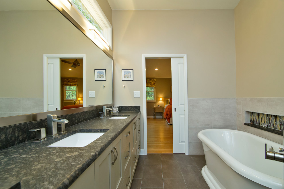 Idéer för att renovera ett mellanstort funkis svart svart en-suite badrum, med skåp i shakerstil, grå skåp, ett fristående badkar, en kantlös dusch, en toalettstol med separat cisternkåpa, beige kakel, porslinskakel, beige väggar, klinkergolv i porslin, ett undermonterad handfat, granitbänkskiva, brunt golv och dusch med gångjärnsdörr