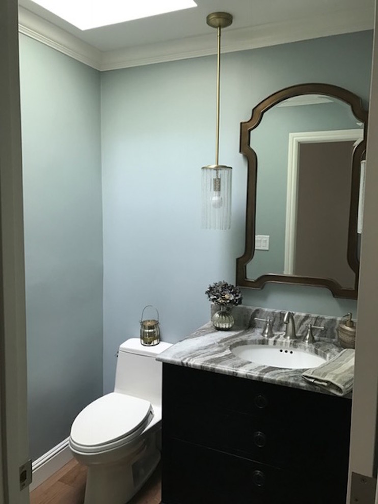 Light green walls with brown and marble sink with a vanity mirror