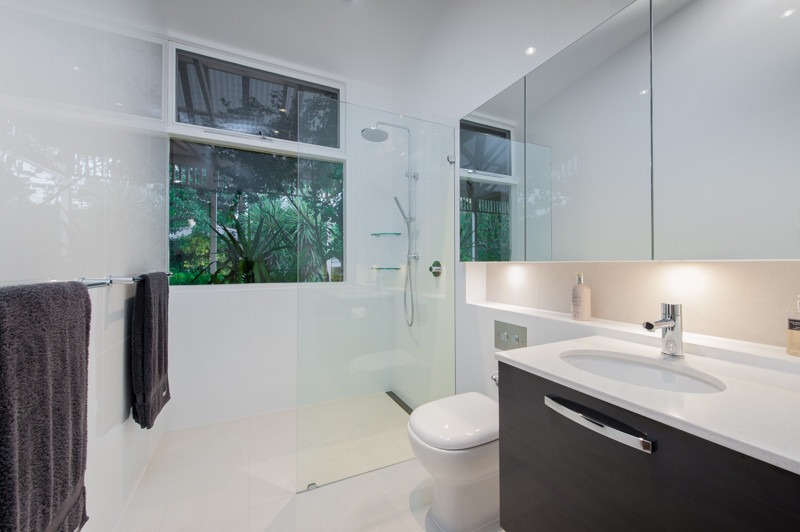 На фото: маленькая главная ванная комната в стиле модернизм с врезной раковиной, коричневыми фасадами, открытым душем, белой плиткой, белыми стенами и полом из керамогранита для на участке и в саду с