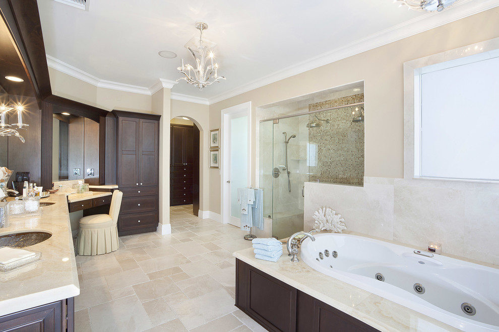 マイアミにあるトラディショナルスタイルのおしゃれな浴室 (アンダーカウンター洗面器、濃色木目調キャビネット、ドロップイン型浴槽、アルコーブ型シャワー、ベージュのタイル) の写真