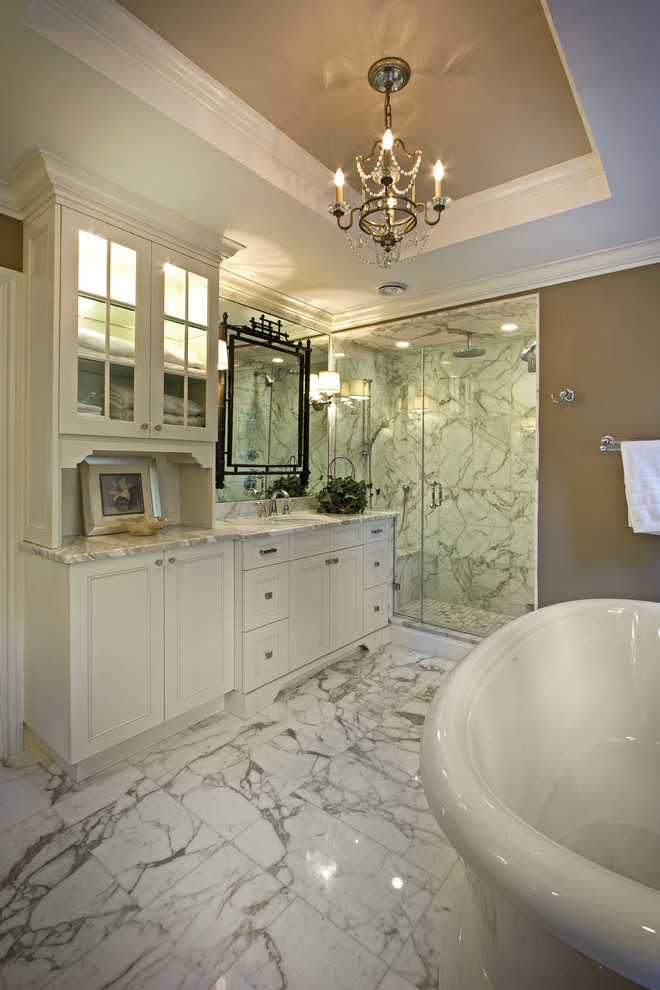 Large contemporary ensuite bathroom in New York with recessed-panel cabinets, white cabinets, a freestanding bath, an alcove shower, grey tiles, white tiles, marble tiles, marble flooring, a submerged sink, marble worktops, grey floors and a hinged door.