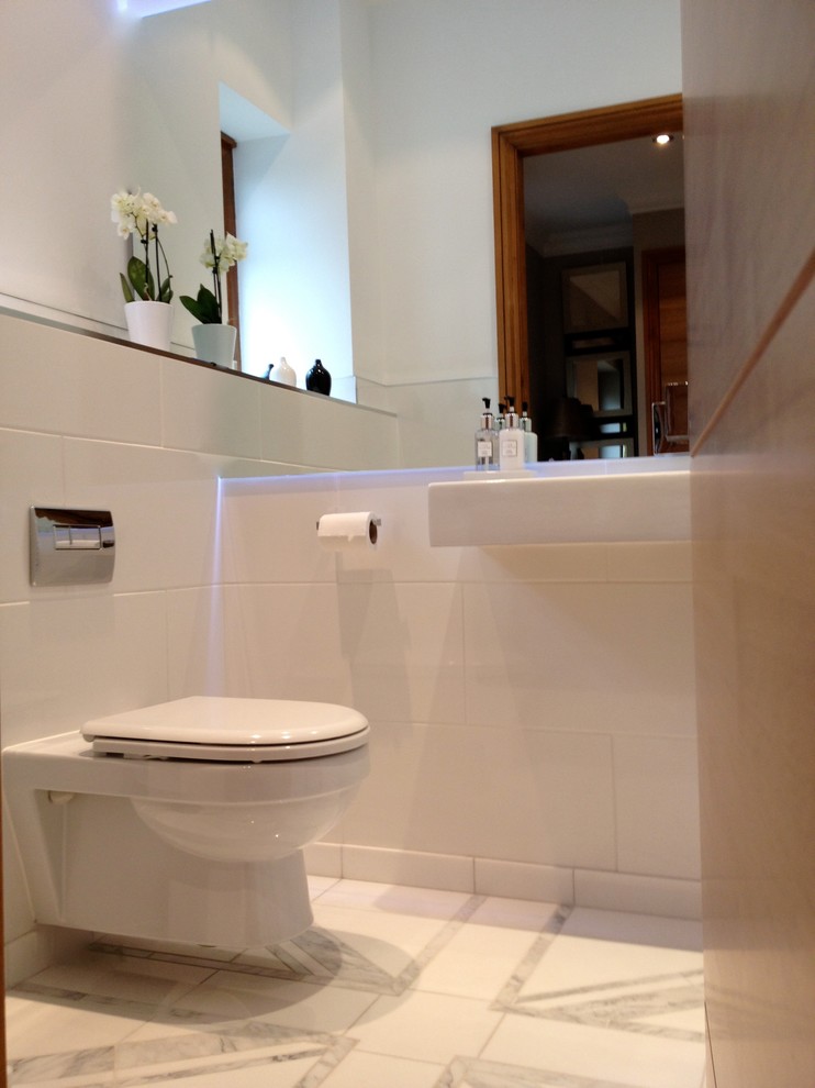 This is an example of a small modern bathroom in Other with a wall-mounted sink, a wall mounted toilet, white tiles, stone tiles, white walls and marble flooring.