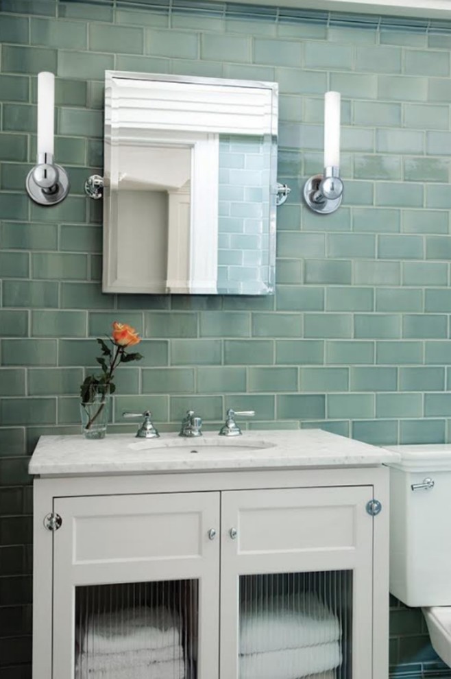 Inredning av ett klassiskt litet badrum med dusch, med luckor med glaspanel, vita skåp, en toalettstol med separat cisternkåpa, grön kakel, tunnelbanekakel, gröna väggar, ett nedsänkt handfat och marmorbänkskiva