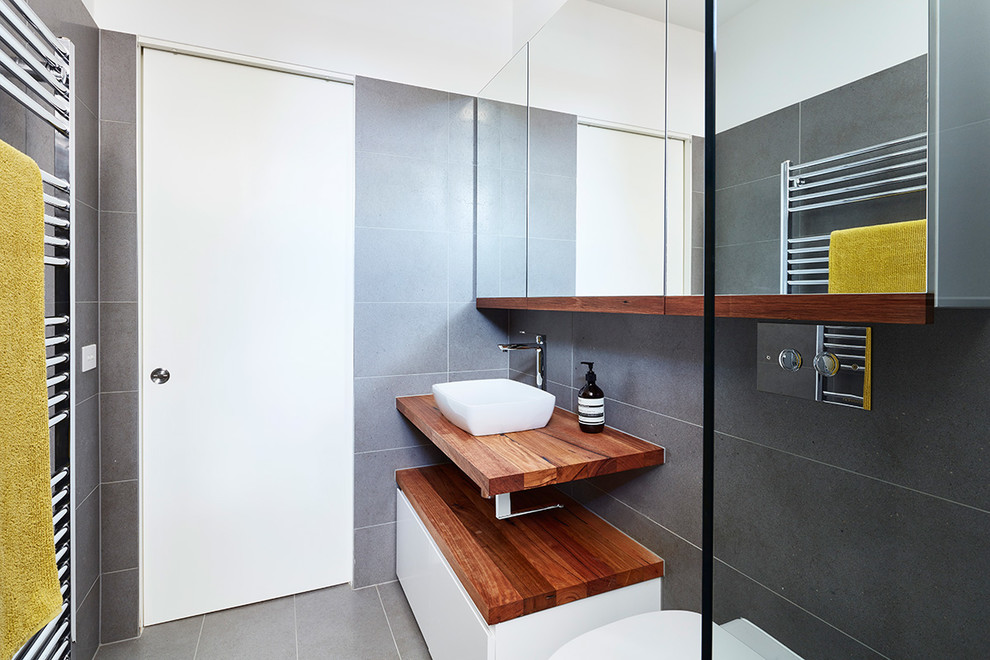 На фото: ванная комната в стиле ретро с серой плиткой, серыми стенами, полом из керамической плитки и столешницей из дерева