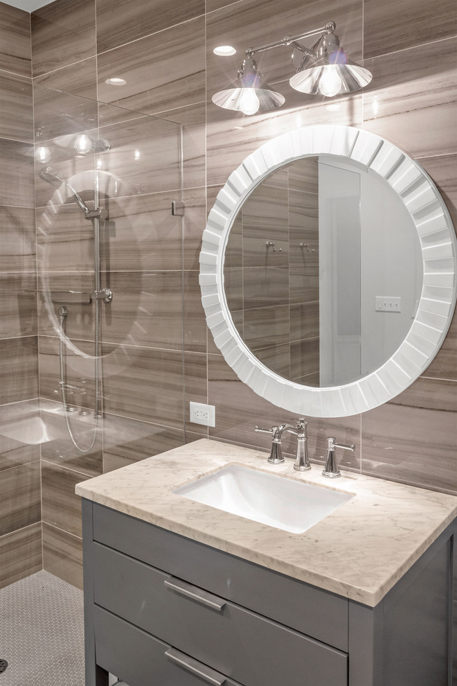 Maritim inredning av ett mellanstort vit vitt badrum med dusch, med möbel-liknande, grå skåp, en öppen dusch, en toalettstol med hel cisternkåpa, brun kakel, porslinskakel, grå väggar, mellanmörkt trägolv, ett undermonterad handfat, marmorbänkskiva, grått golv och med dusch som är öppen