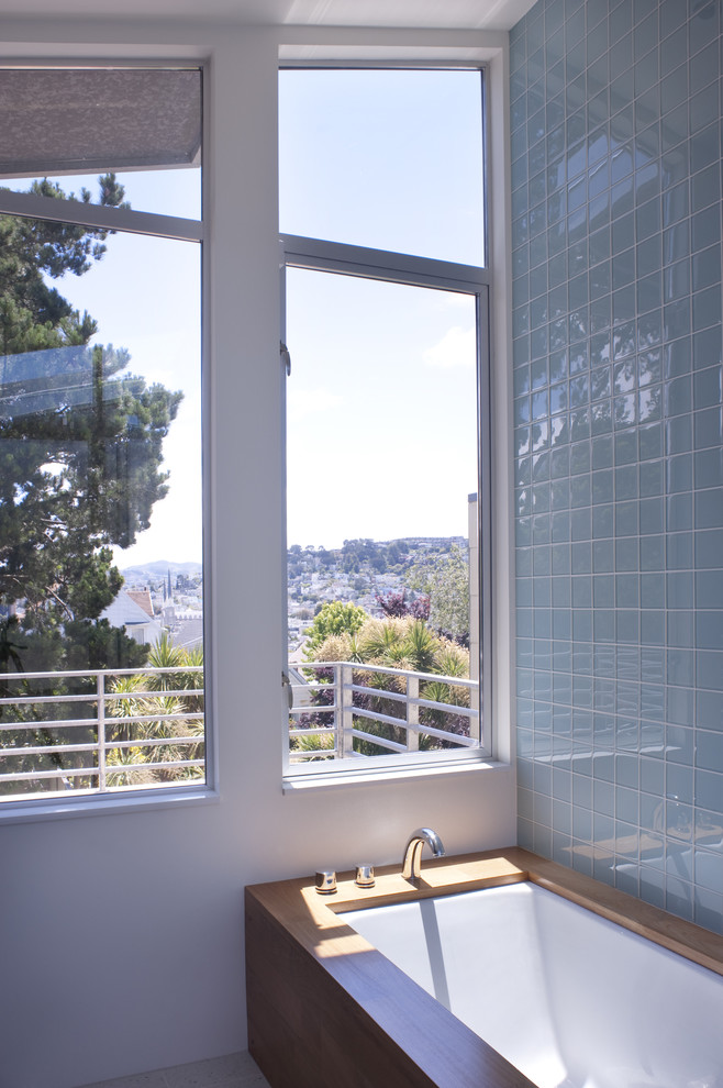 Cette photo montre une salle de bain moderne avec une baignoire encastrée, un carrelage bleu et un carrelage en pâte de verre.