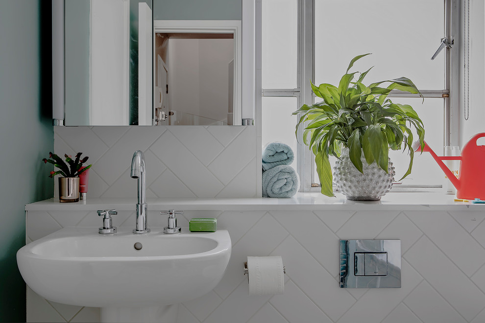This is an example of a small classic family bathroom in Hampshire with a built-in bath, a shower/bath combination, a one-piece toilet, white tiles, ceramic tiles, green walls, vinyl flooring, a wall-mounted sink and green floors.