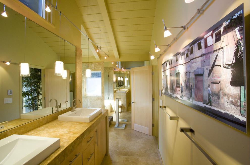 Стильный дизайн: главная ванная комната среднего размера в современном стиле с настольной раковиной, плоскими фасадами, светлыми деревянными фасадами, полновстраиваемой ванной, душем над ванной, желтыми стенами, полом из известняка, столешницей из известняка и плиткой из известняка - последний тренд