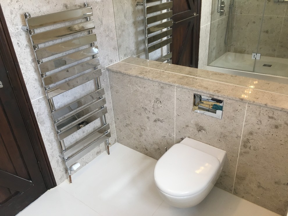 Exempel på ett mellanstort modernt badrum med dusch, med släta luckor, vita skåp, en öppen dusch, en vägghängd toalettstol, beige kakel, kakelplattor, beige väggar, ett undermonterad handfat, bänkskiva i kalksten, vitt golv och dusch med gångjärnsdörr