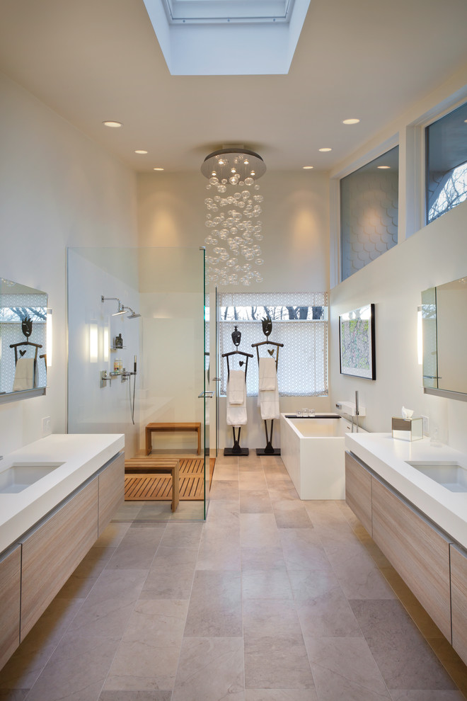 Design ideas for a contemporary bathroom in Minneapolis with grey tiles, stone tiles, limestone flooring, a submerged sink, flat-panel cabinets, a freestanding bath, a corner shower, white walls and light wood cabinets.