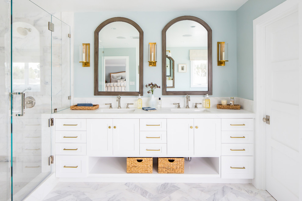 Nautical bathroom in Orange County with shaker cabinets, white cabinets, blue walls, marble flooring, a submerged sink and white floors.
