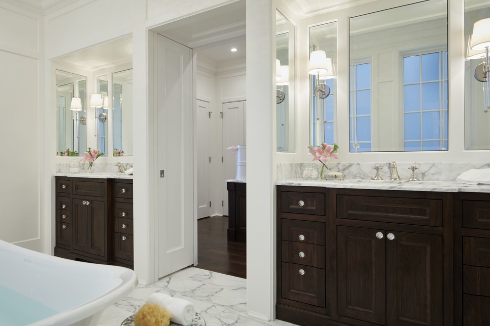 Inredning av ett klassiskt mycket stort en-suite badrum, med luckor med infälld panel, skåp i mörkt trä, ett fristående badkar, en kantlös dusch, en toalettstol med separat cisternkåpa, stenkakel, vita väggar, marmorgolv, ett undermonterad handfat och marmorbänkskiva