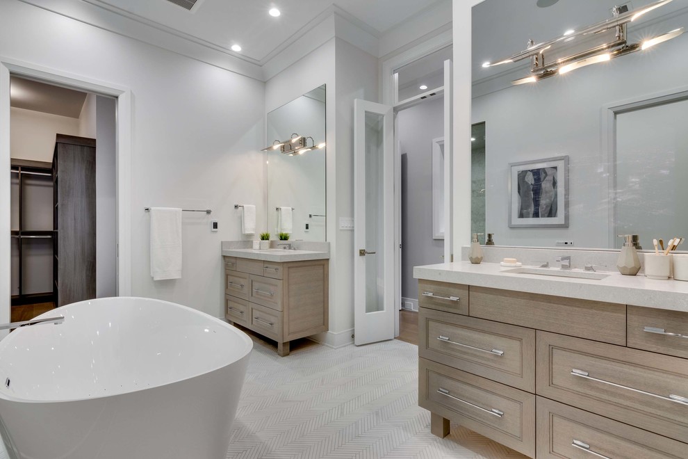Ejemplo de cuarto de baño principal con armarios estilo shaker, puertas de armario de madera clara y bañera exenta