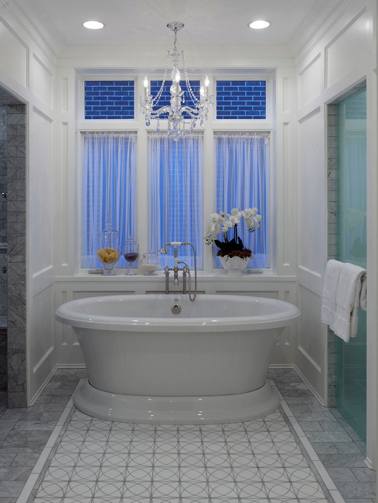 Inspiration for a large traditional ensuite bathroom in Chicago with a submerged sink, freestanding cabinets, white cabinets, marble worktops, a freestanding bath, a built-in shower, a two-piece toilet, grey tiles, stone tiles, white walls and marble flooring.