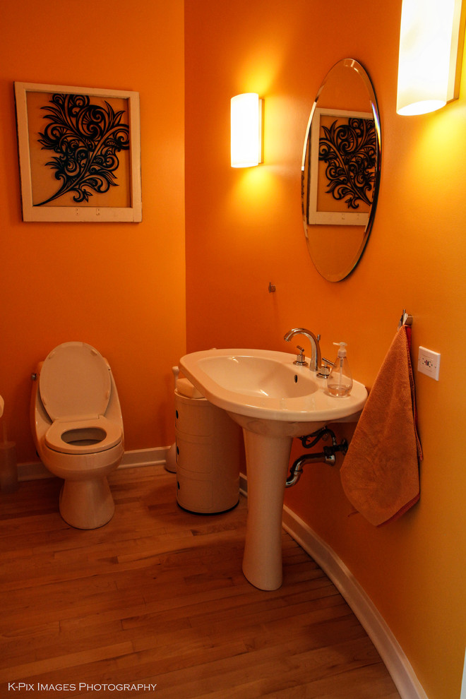 Inspiration för små klassiska badrum med dusch, med ett piedestal handfat, en toalettstol med hel cisternkåpa, orange väggar och ljust trägolv