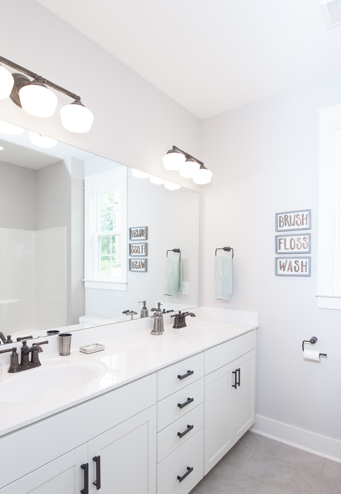 Modelo de cuarto de baño de estilo de casa de campo con armarios estilo shaker, puertas de armario blancas, paredes beige, aseo y ducha y encimeras blancas
