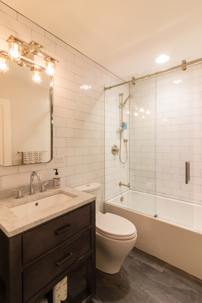 Cette photo montre une salle d'eau chic en bois foncé avec un lavabo encastré, un plan de toilette en marbre, une baignoire en alcôve, un combiné douche/baignoire, un carrelage blanc, un carrelage métro, un mur blanc, un sol en ardoise, un sol gris, une cabine de douche à porte coulissante et un plan de toilette gris.