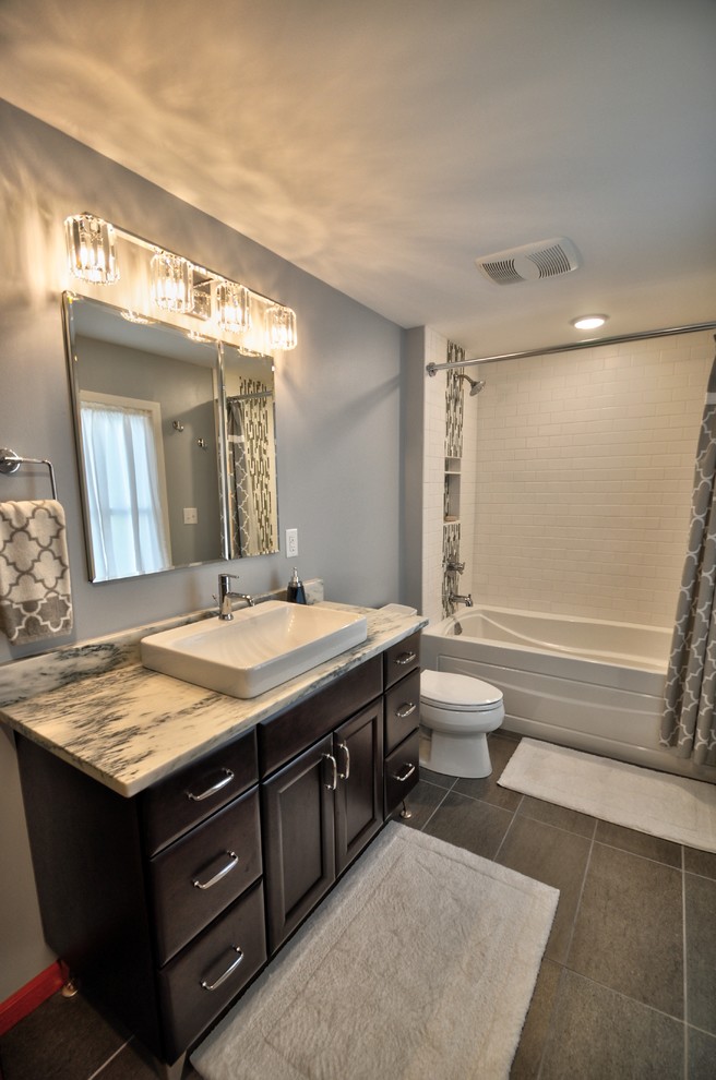 Transitional master white tile and ceramic tile ceramic tile and gray floor bathroom photo in Indianapolis with recessed-panel cabinets, brown cabinets, a two-piece toilet, gray walls, a vessel sink and marble countertops