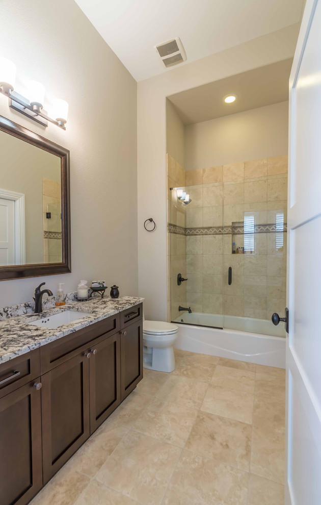 Exempel på ett mellanstort klassiskt flerfärgad flerfärgat badrum med dusch, med luckor med infälld panel, skåp i mörkt trä, ett undermonterat badkar, en dusch/badkar-kombination, en toalettstol med hel cisternkåpa, beige kakel, brun kakel, stenhäll, vita väggar, klinkergolv i porslin, ett undermonterad handfat, granitbänkskiva, beiget golv och dusch med skjutdörr