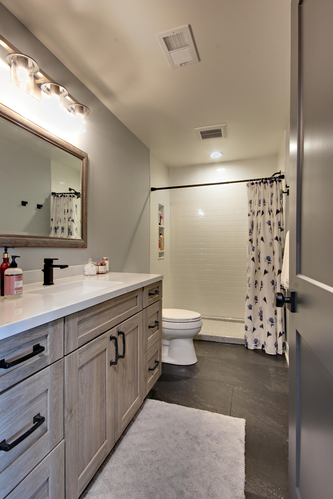 Example of a mid-sized cottage white tile and subway tile slate floor and black floor bathroom design in Grand Rapids with recessed-panel cabinets, light wood cabinets, a two-piece toilet, gray walls, an undermount sink, quartz countertops and white countertops