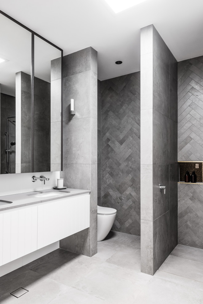 Immagine di una stanza da bagno design con ante lisce, ante bianche, piastrelle grigie, lavabo sottopiano, pavimento grigio e top grigio