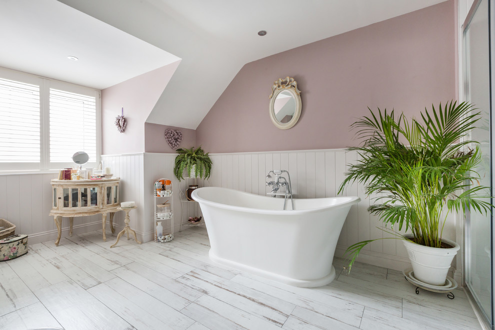 На фото: ванная комната среднего размера в стиле шебби-шик с отдельно стоящей ванной, розовыми стенами и белым полом