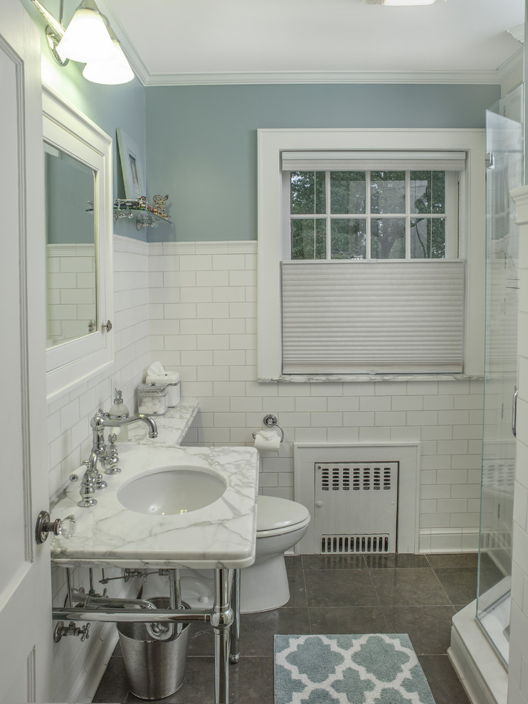 Стильный дизайн: маленькая детская ванная комната в классическом стиле с плоскими фасадами, белыми фасадами, угловым душем, унитазом-моноблоком, белой плиткой, керамической плиткой, бежевыми стенами, полом из известняка, консольной раковиной, мраморной столешницей, коричневым полом, душем с распашными дверями и белой столешницей для на участке и в саду - последний тренд
